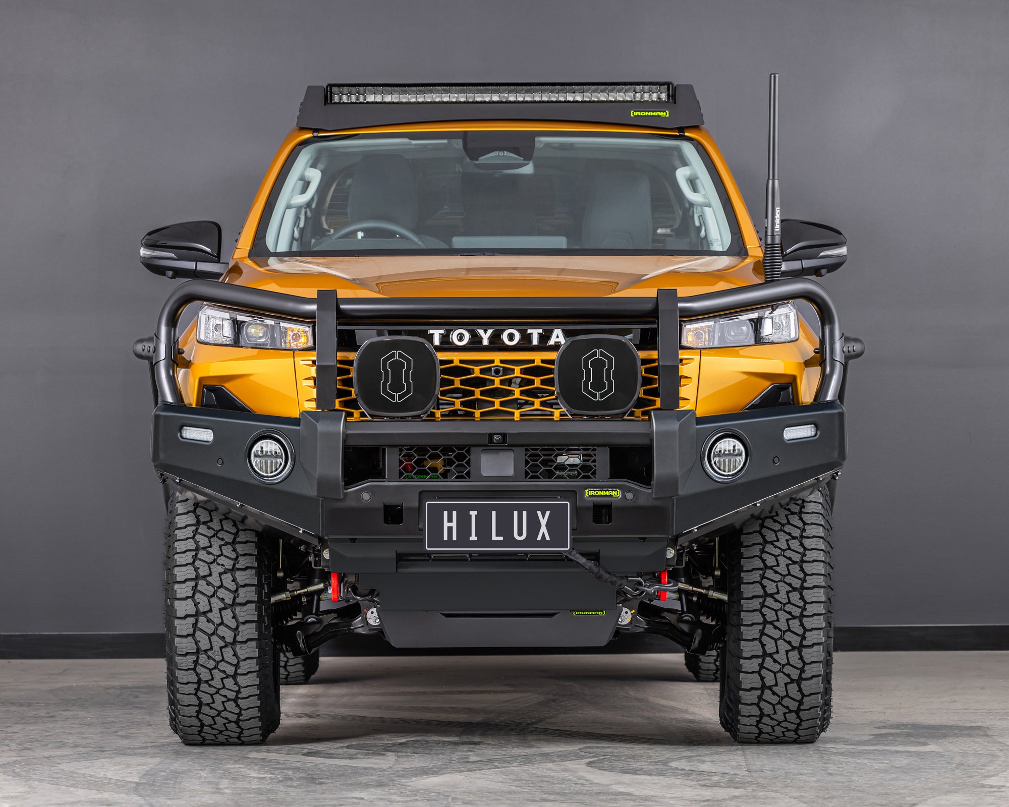 toyota hilux n90 2026 sunglow orange with ironman 4x4 deluxe bull bar front angle also showing raid roof rack with integrated led light bar