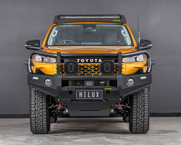 toyota hilux n90 2026 sunglow orange with ironman 4x4 deluxe bull bar front angle also showing raid roof rack with integrated led light bar